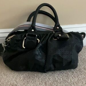 Perforated vegan leather handheld, duffel satchel, includes crossbody strap.